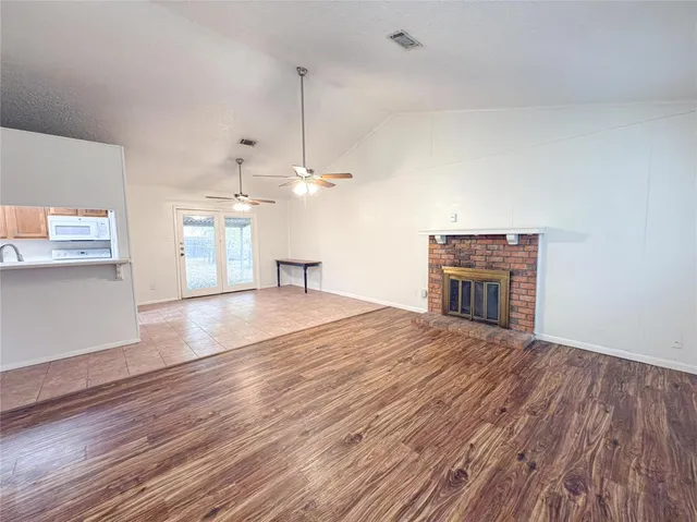 a view of empty room with wooden floor and kitchen view
