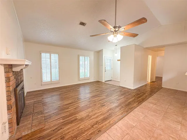 a view of an empty room with window and wooden floor