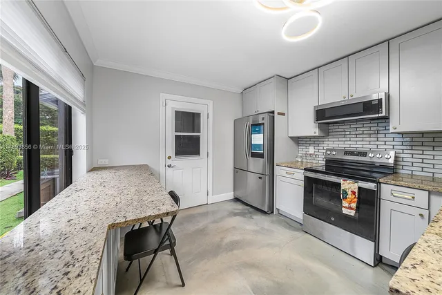 a kitchen with granite countertop a stove a sink and a refrigerator