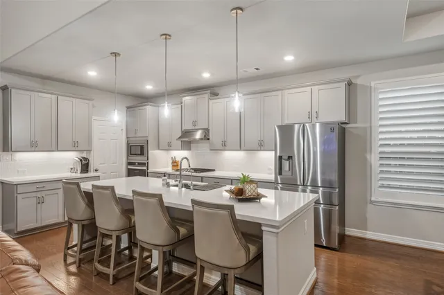 a kitchen with kitchen island granite countertop a table chairs stove and refrigerator