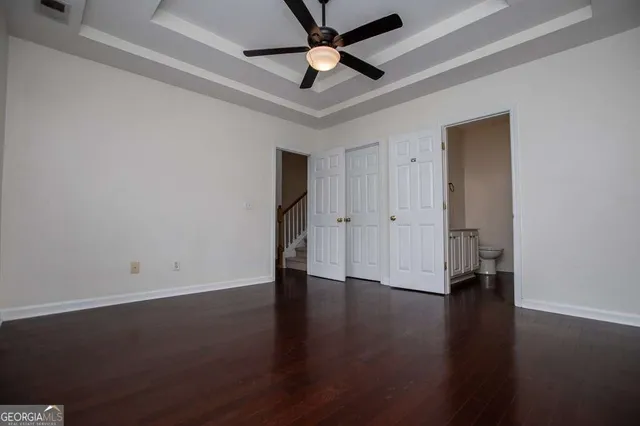 an empty room with wooden floor a ceiling fan and closet