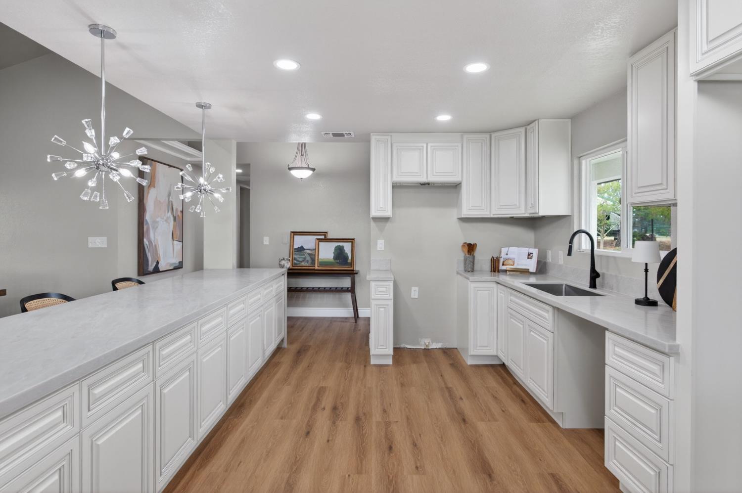 16564 Monreal Road Madera, CA 93636 - Photo 16 of 59 a large kitchen with kitchen island a large counter space a sink stainless steel appliances and cabinets