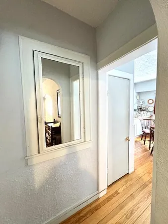 a view of a hallway with wooden floor and a living room