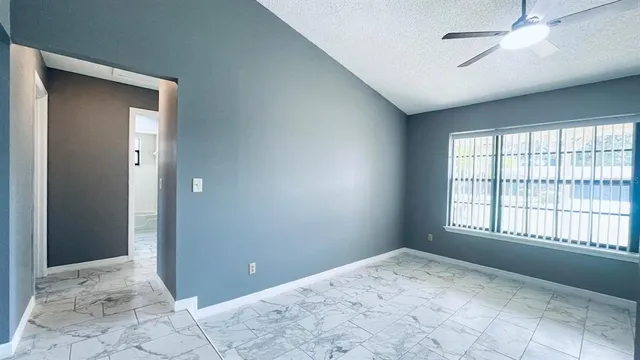 a view of an empty room with window and chandelier fan