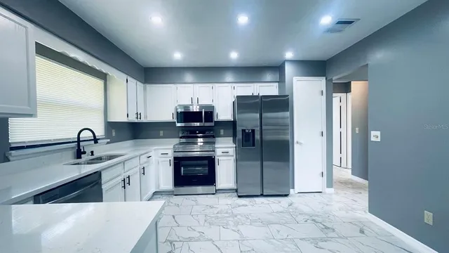 a kitchen with stainless steel appliances granite countertop a refrigerator and a sink