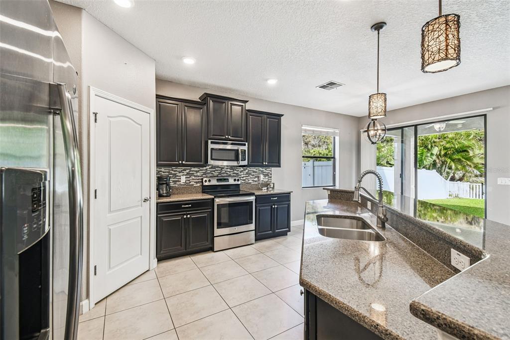 11737 Crestridge Loop New Port Richey, FL 34655 - Photo 29 of 100 a kitchen with stainless steel appliances granite countertop a sink stove and refrigerator