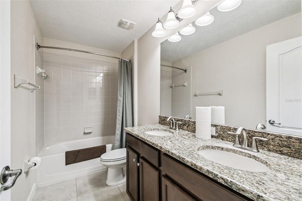 11737 Crestridge Loop New Port Richey, FL 34655 - Photo 58 of 100 a bathroom with a granite countertop double vanity sink a toilet a mirror and shower