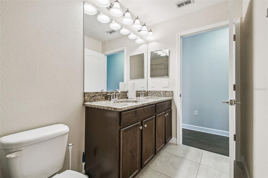 11737 Crestridge Loop New Port Richey, FL 34655 - Photo 59 of 100 a bathroom with a granite countertop sink a toilet and a mirror