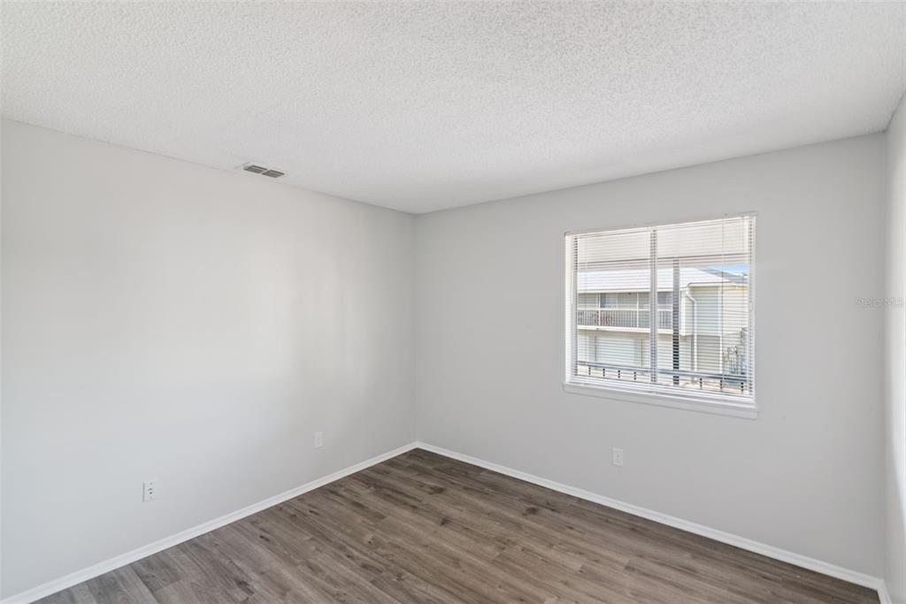4449 Ring Neck Road, Unit C Orlando, FL 32808 - Photo 19 of 29 an empty room with wooden floor and windows