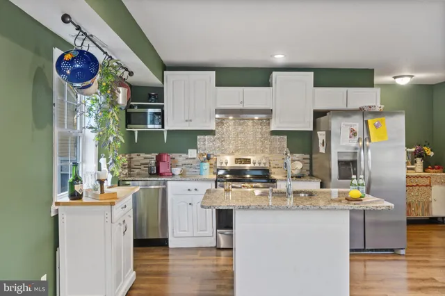 a kitchen with a refrigerator a stove a microwave a sink and wooden floor