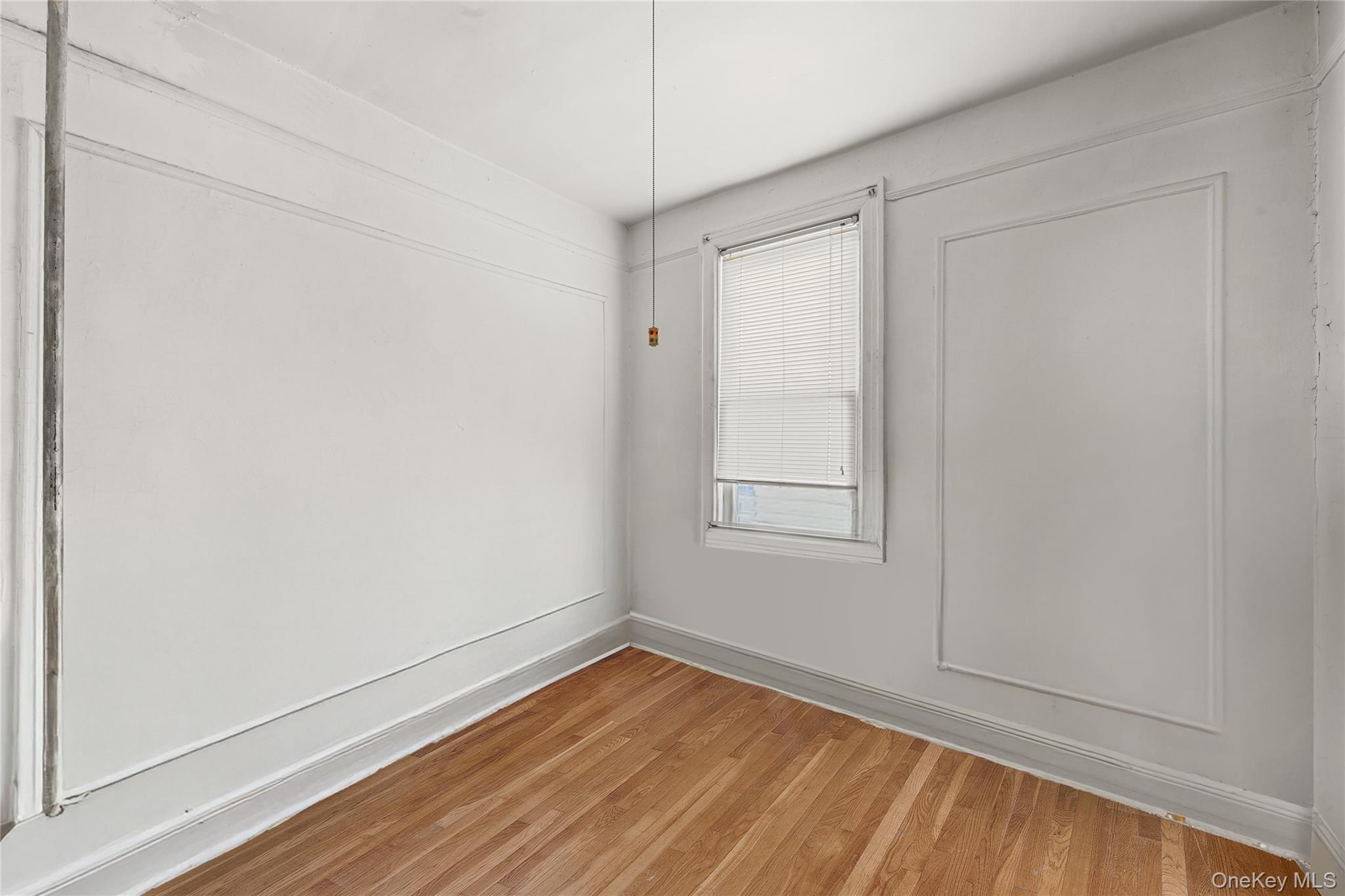39-27 57th Street Queens, NY 11377 - Photo 12 of 35 a view of an empty room with wooden floor and a window