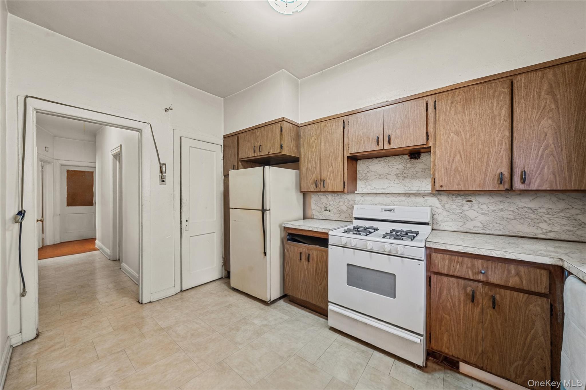 39-27 57th Street Queens, NY 11377 - Photo 24 of 35 a kitchen with white cabinets and white appliances