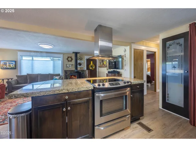 a kitchen with stainless steel appliances granite countertop a refrigerator a stove and a sink with wooden cabinets