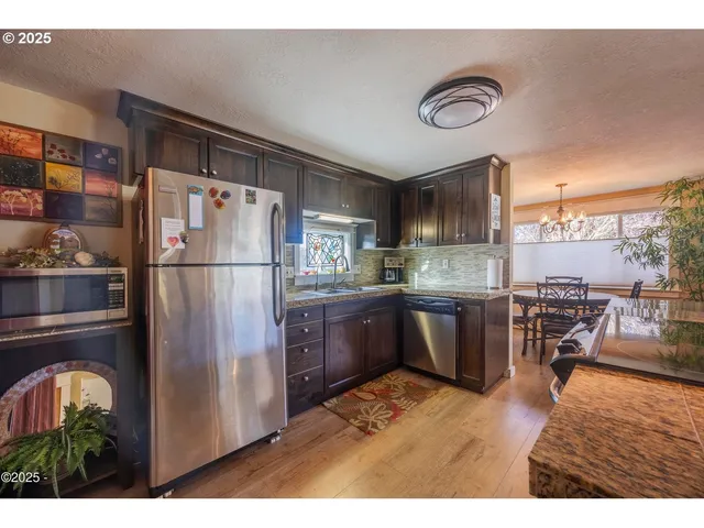 a kitchen with stainless steel appliances granite countertop a sink a stove top oven a refrigerator and dishwasher