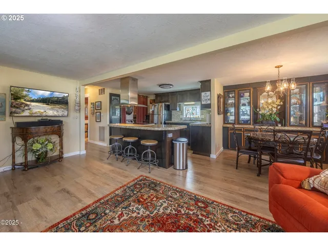 a living room with stainless steel appliances kitchen island granite countertop furniture and a wooden floor