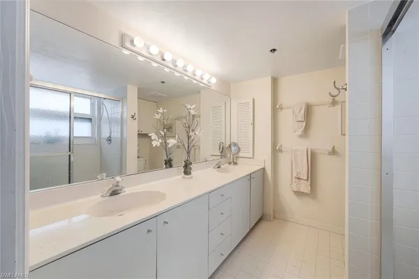 a bathroom with a double vanity sink mirror and shower