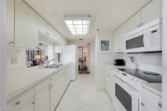 a kitchen with a sink dishwasher stove and white cabinets