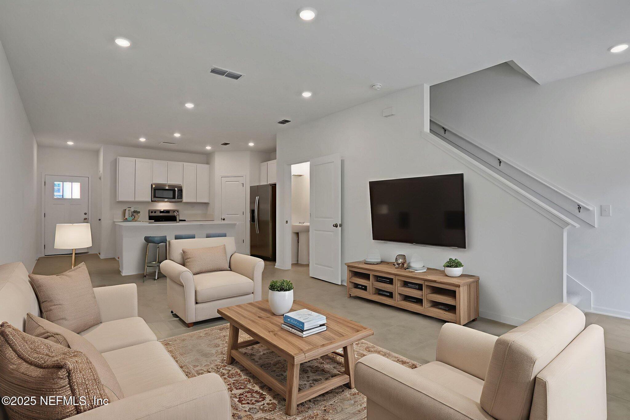 3765 Athenian Way Middleburg, FL 32068 - Photo 25 of 61 a living room with furniture and a flat screen tv with kitchen view