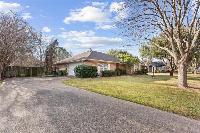 a front view of a house with a yard and a large tree