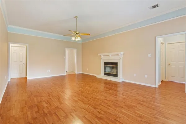 a view of an empty room with wooden floor fireplace and a window