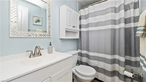 a bathroom with a sink a toilet a mirror and shower curtain