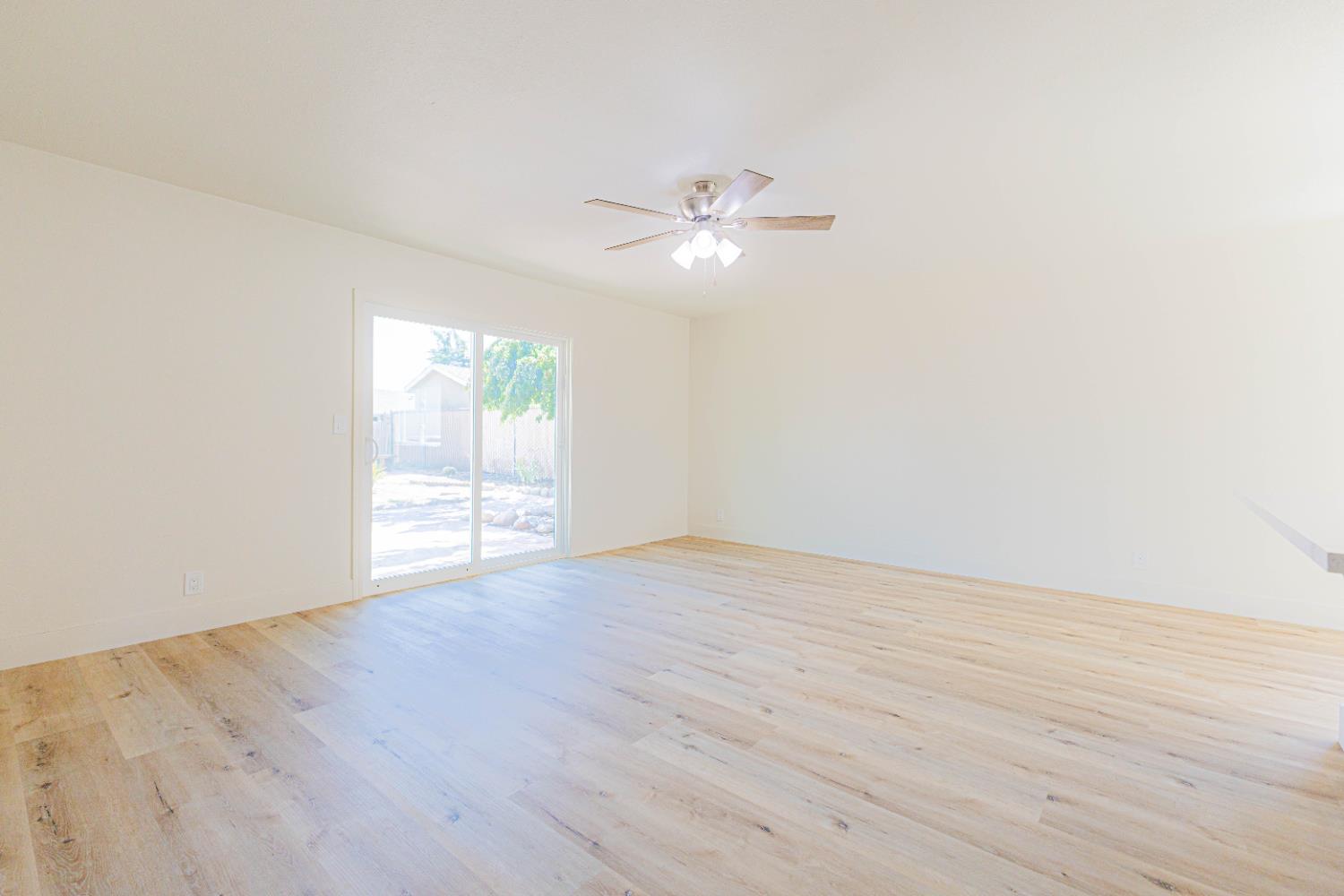 4680 East Grove Avenue Fresno, CA 93725 - Photo 2 of 19 a view of an empty room with wooden floor and a window