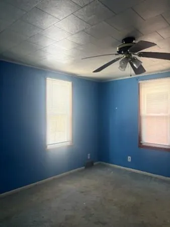 an empty room with windows and a ceiling fan