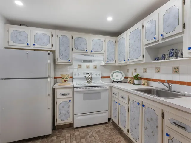 a kitchen with kitchen island white cabinets and refrigerator