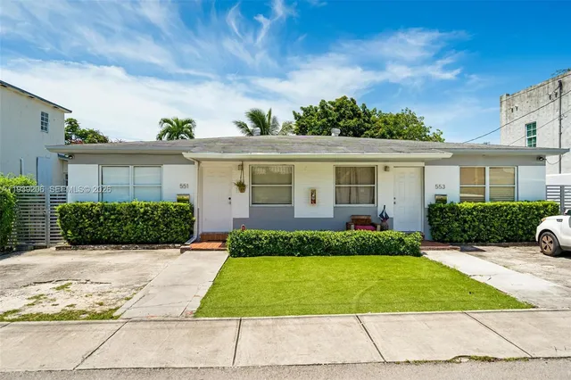 a front view of a house with a yard and potted plants