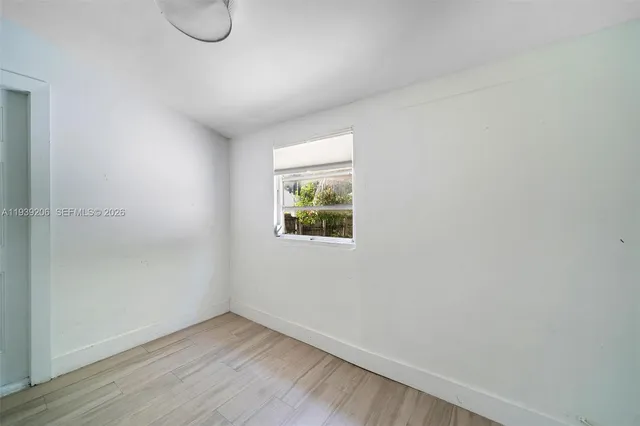 a view of an empty room with wooden floor and a window