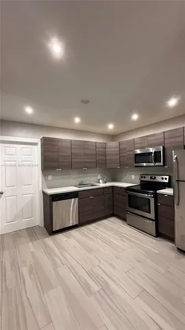 a large kitchen with a large counter top stainless steel appliances and cabinets