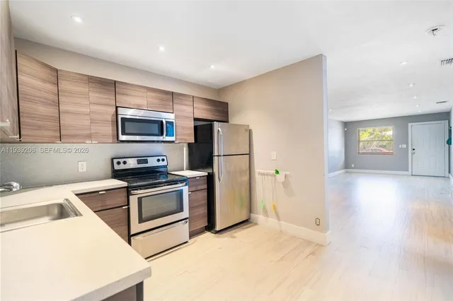 a kitchen that has a refrigerator a stove and white cabinets with wooden floor