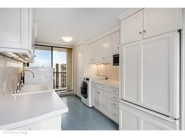 a kitchen with white cabinets and refrigerator