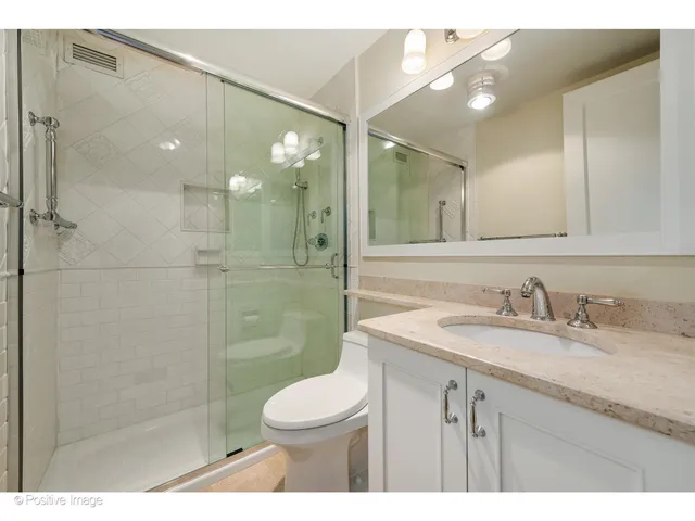 a bathroom with a granite countertop sink a toilet and shower