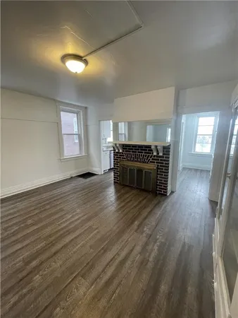 an empty room with wooden floor and fire place