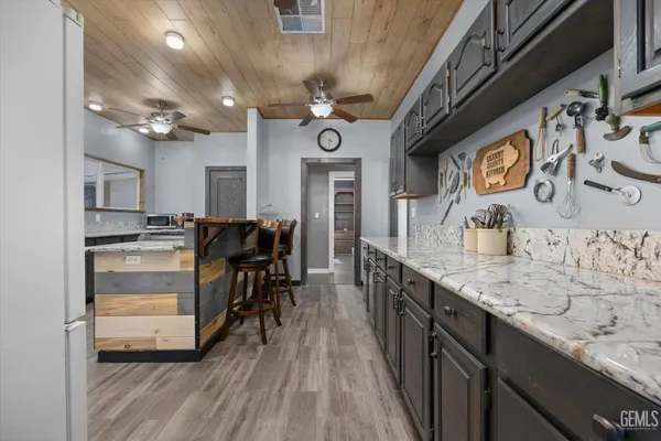 a kitchen with kitchen island granite countertop a sink cabinets and stainless steel appliances