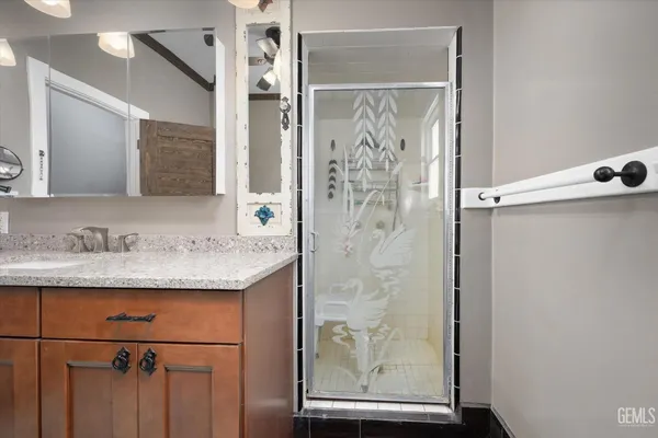 a bathroom with a granite countertop sink mirror and a shower