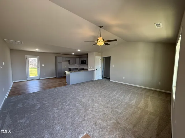 a view of empty room with kitchen and window