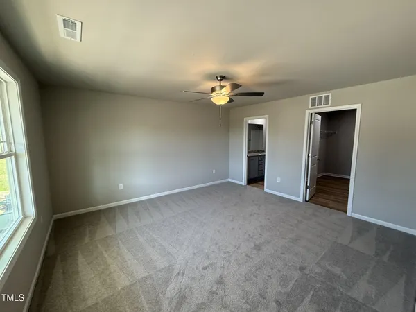 an empty room with chandelier fan and windows