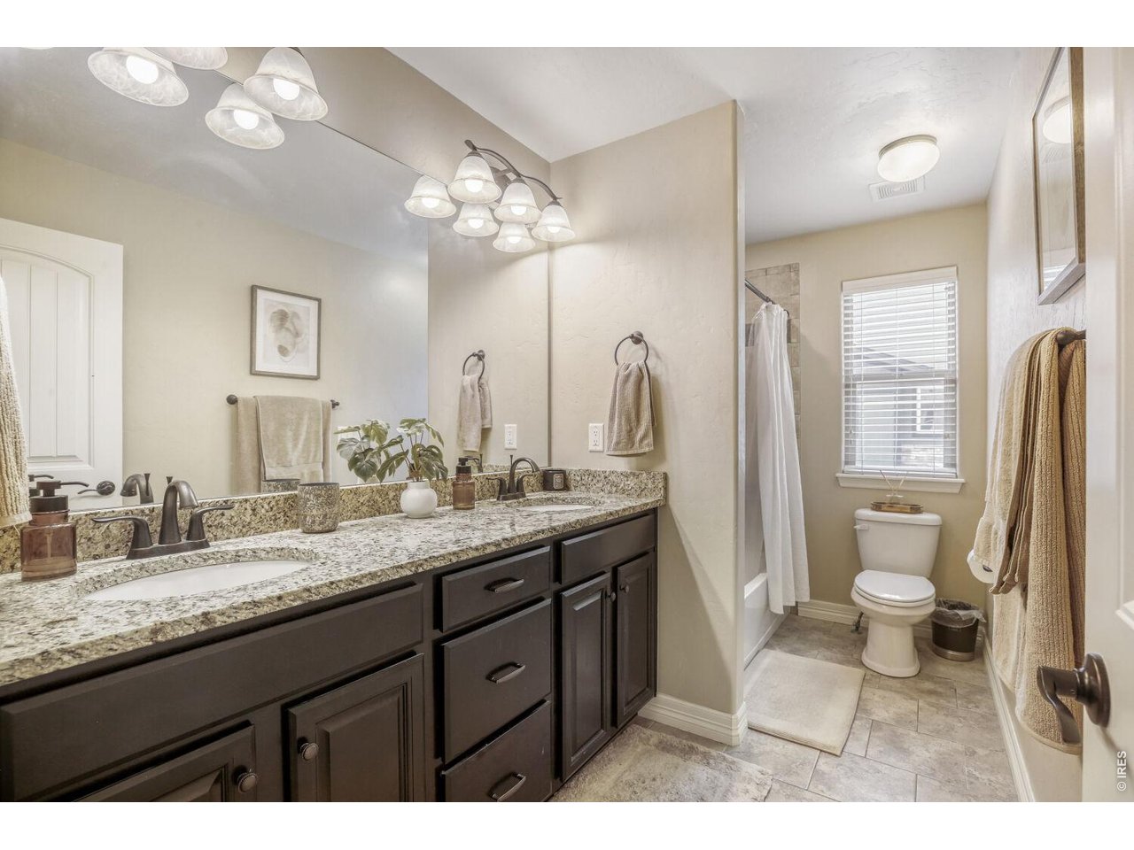 7992 St Street Frederick, CO 80530 - Photo 22 of 28 a bathroom with a granite countertop sink a toilet a mirror and shower