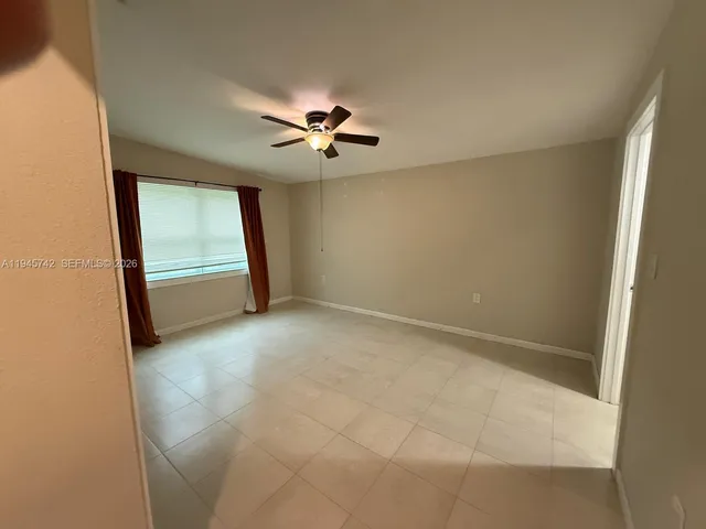 an empty room with windows and fan