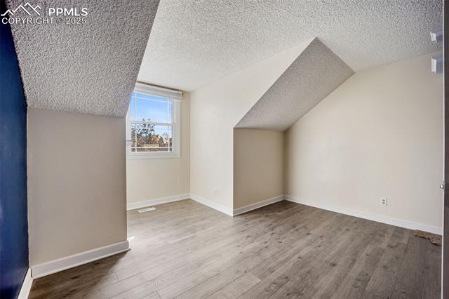 103 Saddlemountain Road Colorado Springs, CO 80919 - Photo 20 of 30 Bonus room featuring a textured ceiling, wood finished floors, and vaulted ceiling