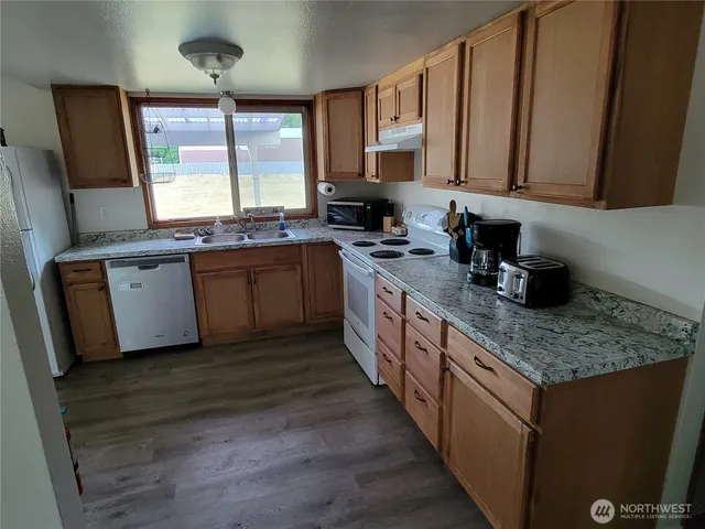 a large kitchen with stainless steel appliances granite countertop wooden cabinets a sink and dishwasher