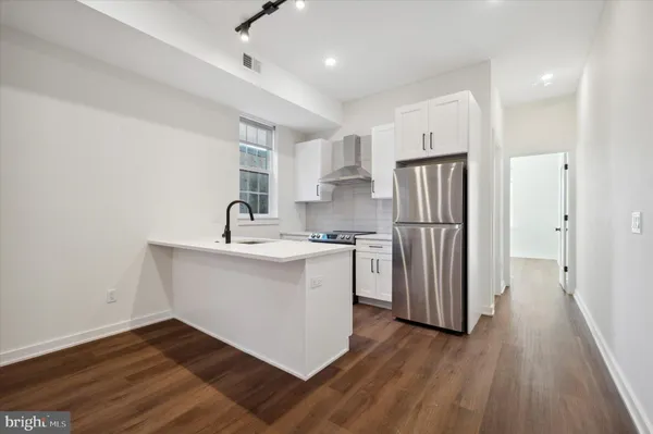 a kitchen with a sink stainless steel appliances and wooden floor