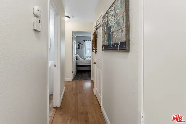 a view of a hallway with wooden floor and a bathroom