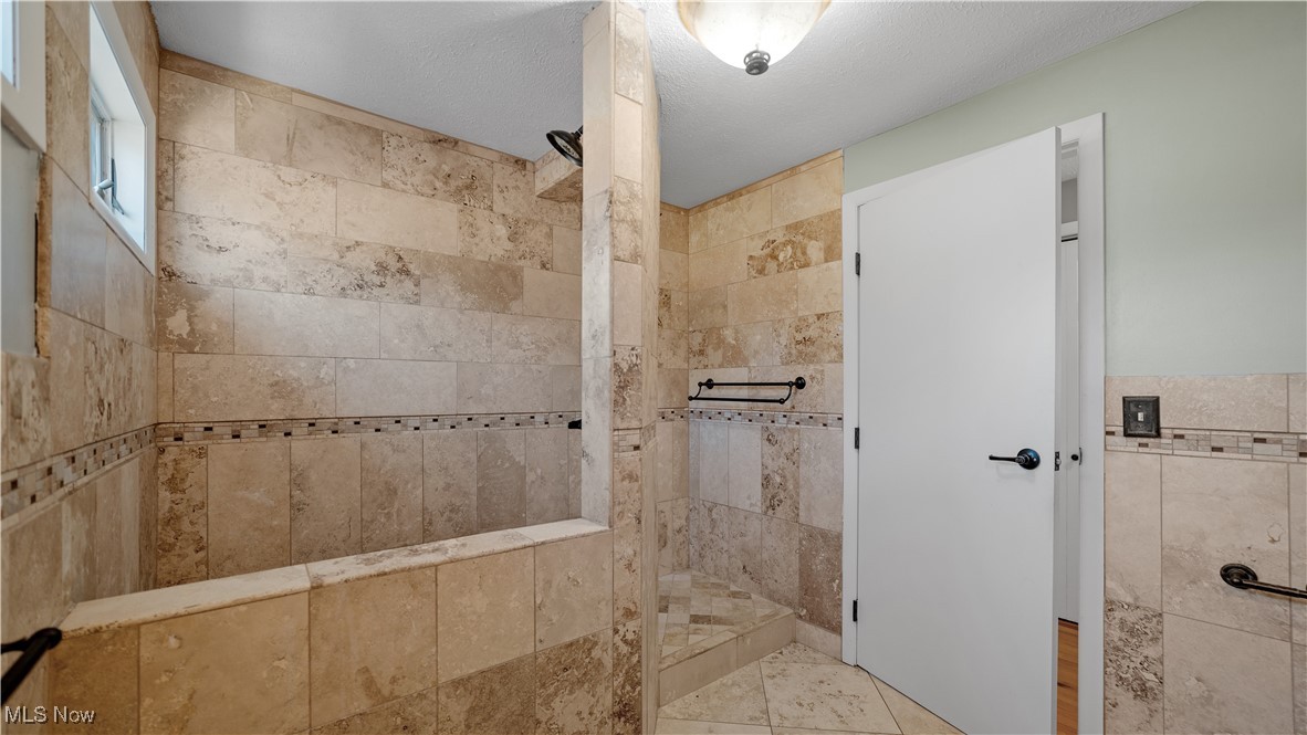 546 Twitchell Road Mansfield, OH 44903 - Photo 18 of 47 Bathroom with tile walls, tile patterned flooring, a textured ceiling, and tiled shower