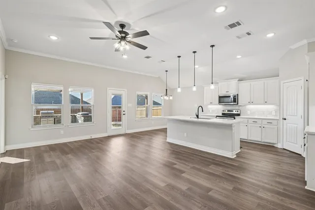 a large white kitchen with lots of counter space wooden floor and appliances