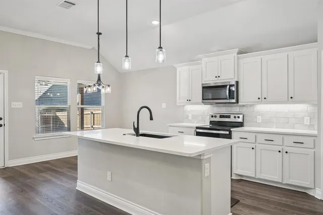 a kitchen with stainless steel appliances kitchen island a white cabinets and wooden floor