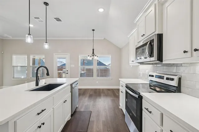 a kitchen with stainless steel appliances granite countertop a sink a stove and a wooden floors