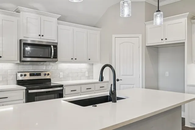 a kitchen with stainless steel appliances a stove a sink a microwave and cabinets